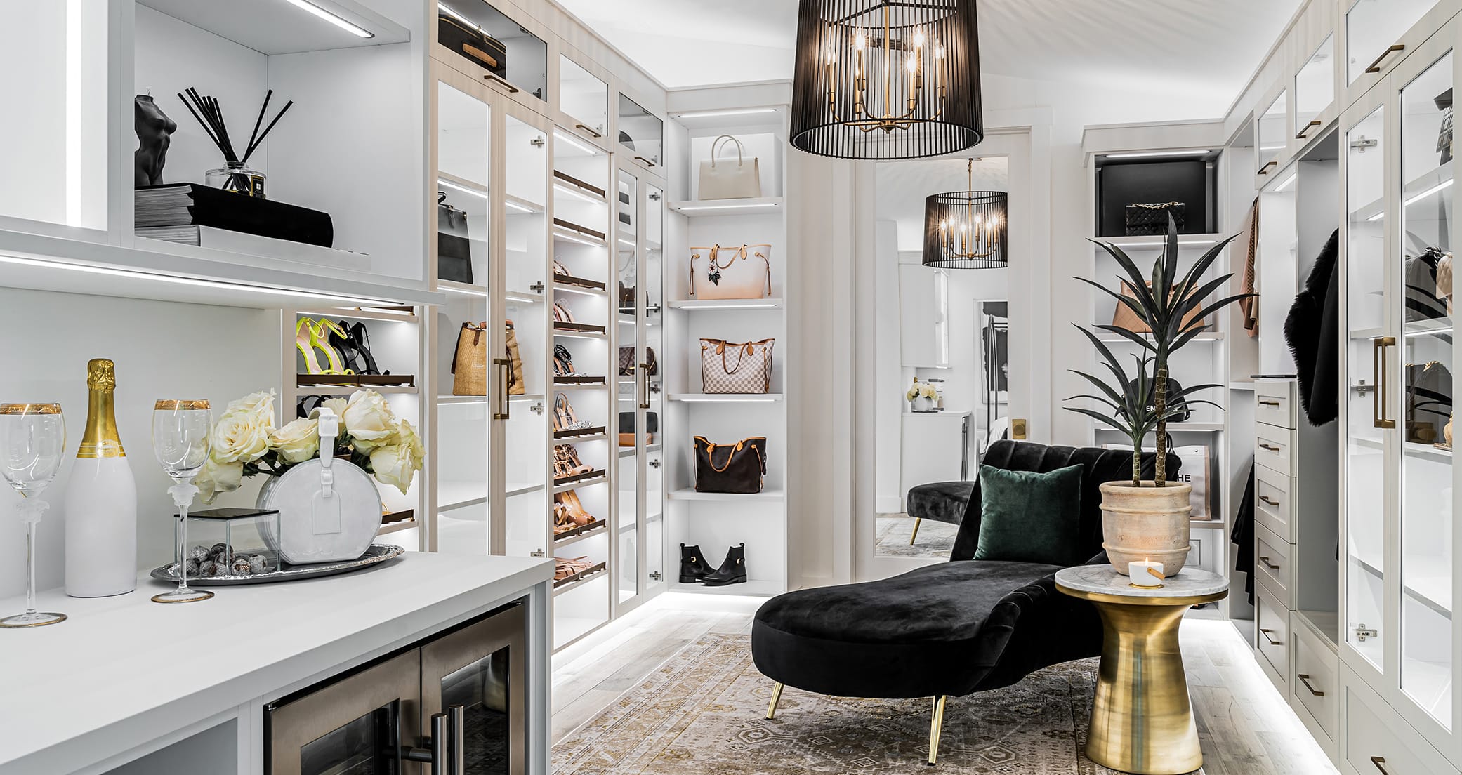 Luxury walk in closet with shoe storage and custom led lighting throughout by California Closets